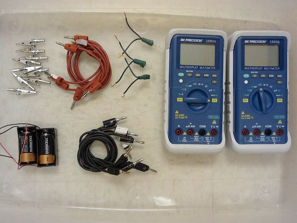 Digital multimeters, test leads and small components arranged for electrical measurements
