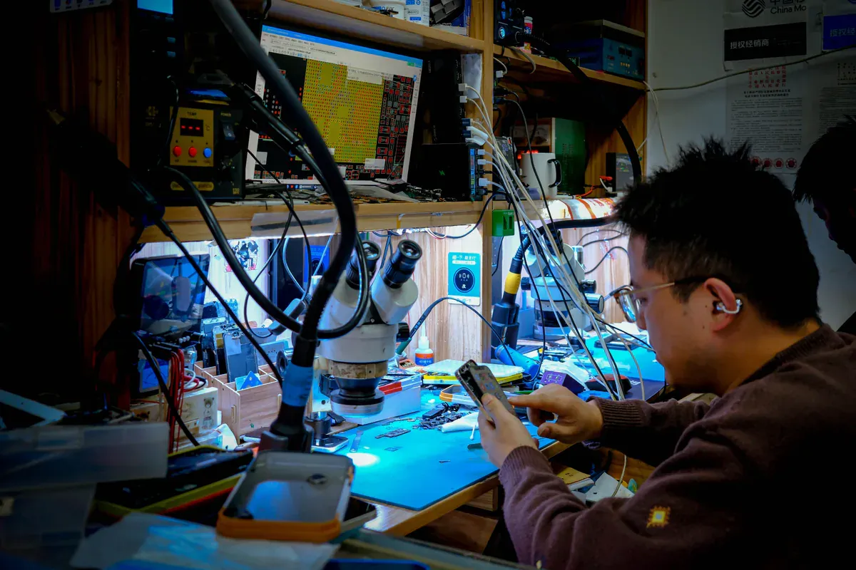 Technician working on an electronic assembly under a bench light
