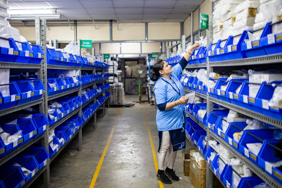 Worker checking labeled storage bins on warehouse shelves